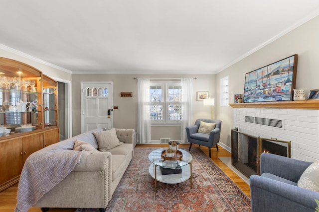 living room featuring ornamental molding, hardwood / wood-style floors, and a brick fireplace