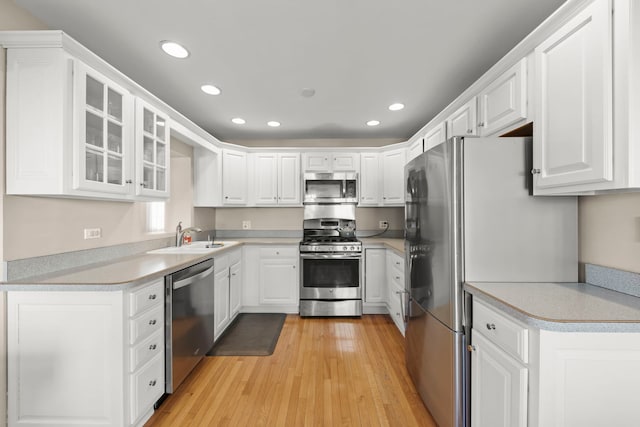 kitchen with white cabinetry, appliances with stainless steel finishes, sink, and light wood-type flooring