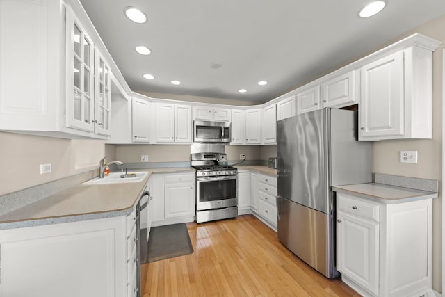 kitchen with white cabinetry, appliances with stainless steel finishes, light hardwood / wood-style floors, and sink