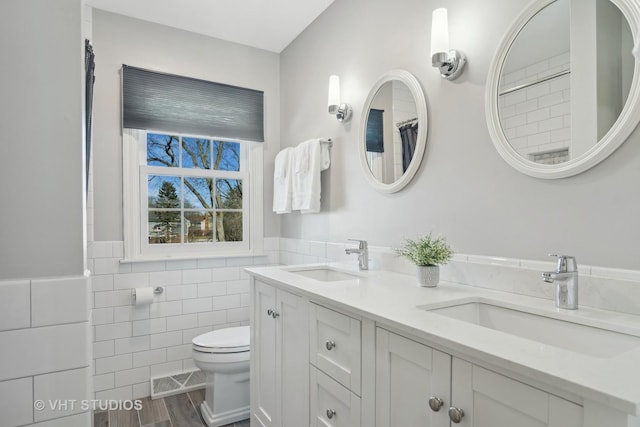 bathroom with tile walls, toilet, and vanity