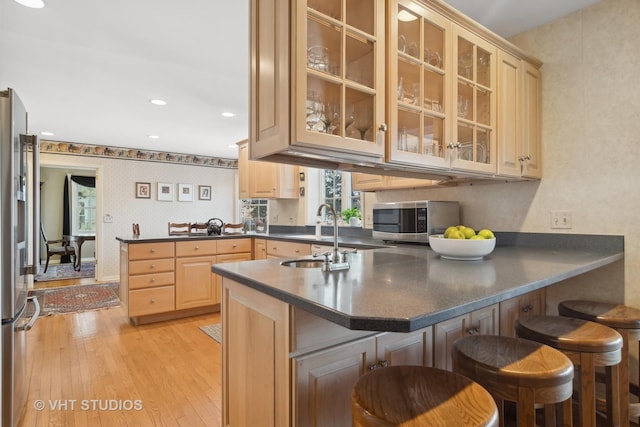 kitchen with sink, light brown cabinets, a kitchen bar, kitchen peninsula, and appliances with stainless steel finishes