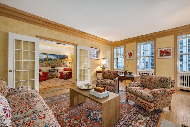 living room featuring hardwood / wood-style floors, ornamental molding, french doors, and radiator heating unit