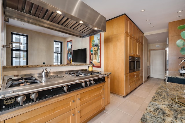 kitchen featuring stainless steel gas cooktop, light stone counters, oven, island range hood, and light tile patterned floors