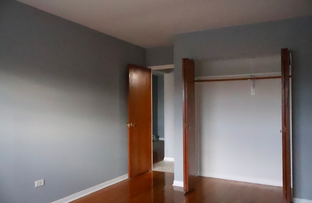 unfurnished bedroom featuring dark wood-type flooring and a closet