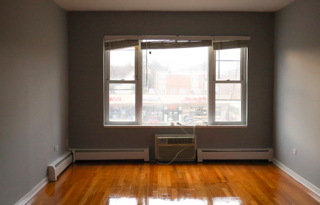 unfurnished room featuring a wall mounted AC, baseboard heating, and light hardwood / wood-style flooring