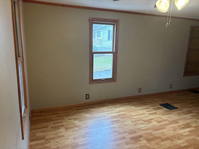 empty room with crown molding and light wood-type flooring