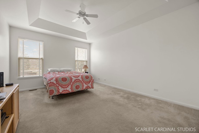 bedroom featuring baseboards, a tray ceiling, and light colored carpet