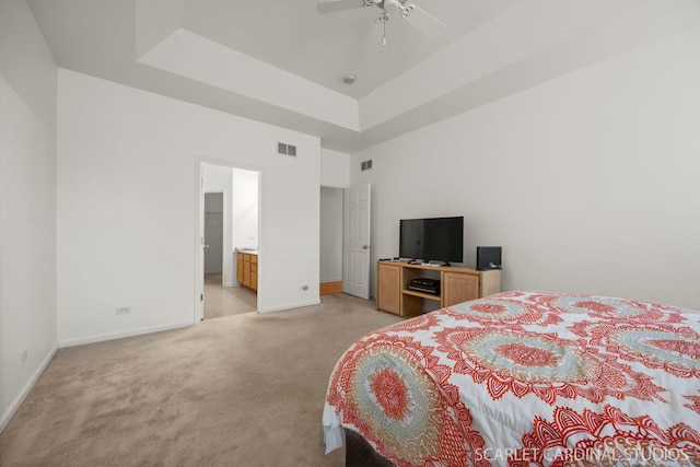 bedroom with baseboards, a tray ceiling, visible vents, and light colored carpet