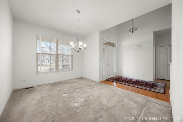 unfurnished dining area featuring baseboards, visible vents, a notable chandelier, and carpet flooring