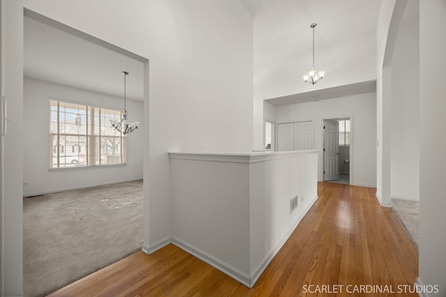 hall with an inviting chandelier, plenty of natural light, and wood finished floors