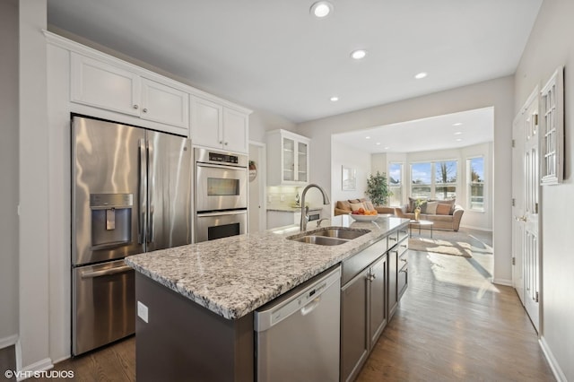 kitchen with dark hardwood / wood-style floors, sink, an island with sink, stainless steel appliances, and white cabinets