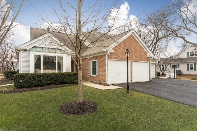 view of front facade with brick siding, an attached garage, central AC unit, driveway, and a front lawn