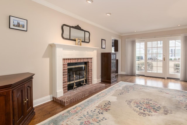 living area featuring baseboards, a fireplace, ornamental molding, and wood finished floors