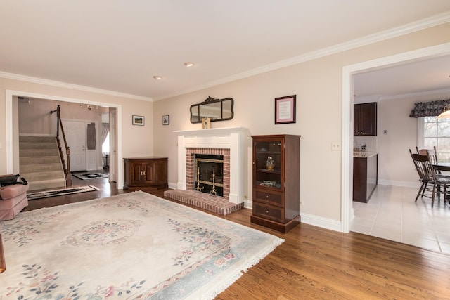 interior space featuring a fireplace, crown molding, light wood finished floors, stairway, and baseboards