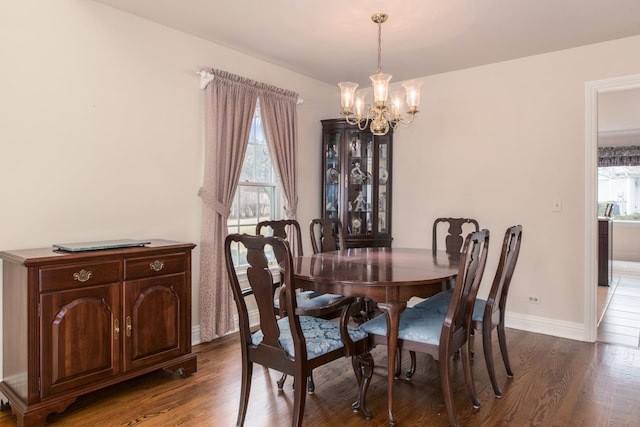 dining area featuring baseboards, wood finished floors, and a notable chandelier