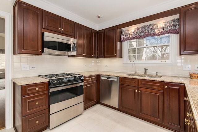 kitchen featuring appliances with stainless steel finishes, a sink, light stone countertops, crown molding, and backsplash