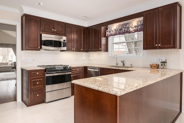 kitchen featuring light stone counters, stainless steel appliances, a peninsula, a sink, and decorative backsplash