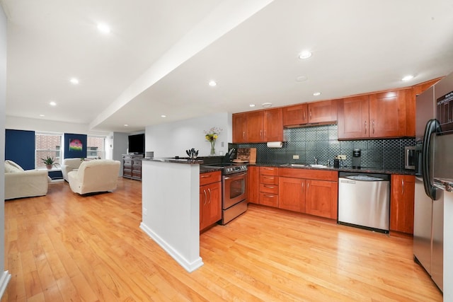 kitchen featuring stainless steel appliances, tasteful backsplash, light hardwood / wood-style floors, and dark stone countertops