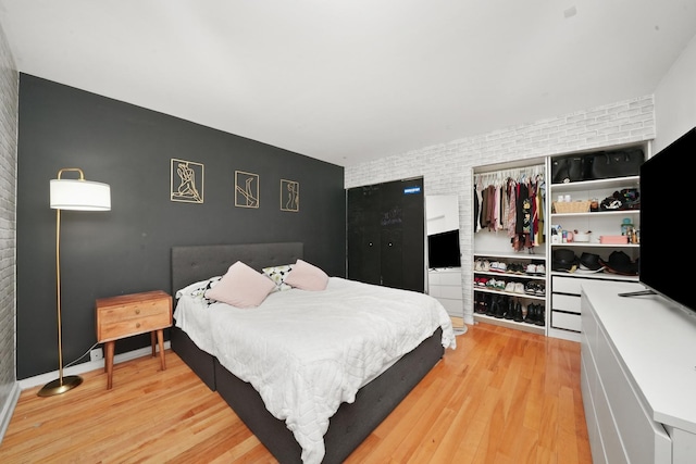 bedroom featuring light hardwood / wood-style flooring and brick wall