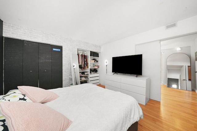 bedroom with hardwood / wood-style flooring and brick wall