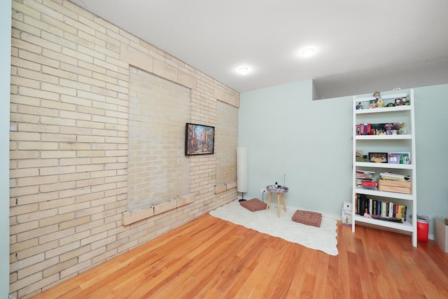 playroom with hardwood / wood-style floors and brick wall