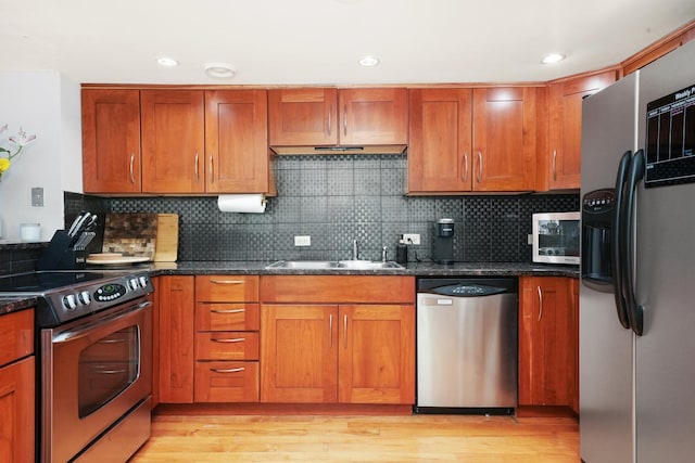 kitchen featuring stainless steel appliances, tasteful backsplash, dark stone countertops, and sink