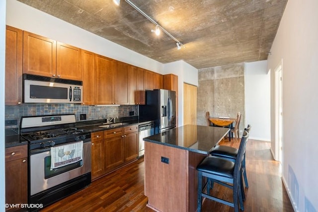 kitchen with sink, a center island, dark hardwood / wood-style floors, a breakfast bar, and appliances with stainless steel finishes