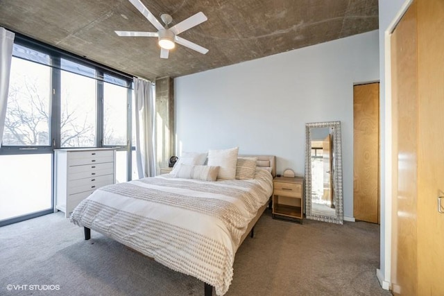 carpeted bedroom with ceiling fan, a closet, and a wall of windows