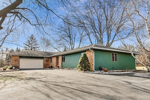 ranch-style house featuring a garage, driveway, and brick siding