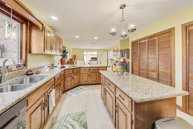 kitchen featuring appliances with stainless steel finishes, sink, pendant lighting, an inviting chandelier, and a kitchen island