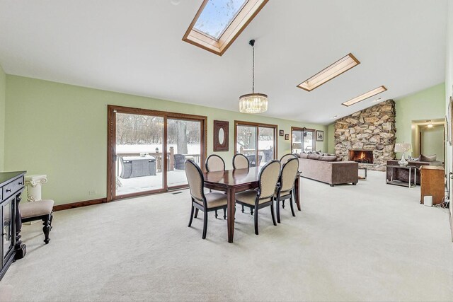 carpeted living room with a fireplace, lofted ceiling with skylight, and a healthy amount of sunlight