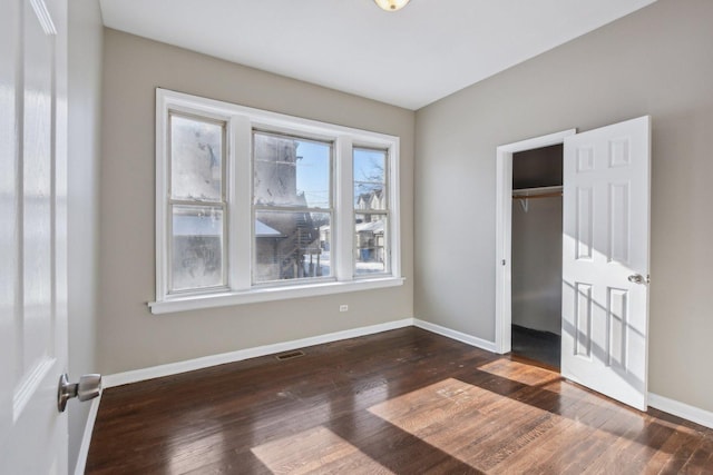 unfurnished bedroom with multiple windows, dark hardwood / wood-style flooring, and a closet