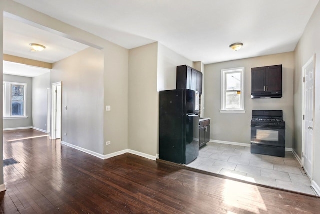 kitchen with dark brown cabinets, black appliances, and light wood-type flooring