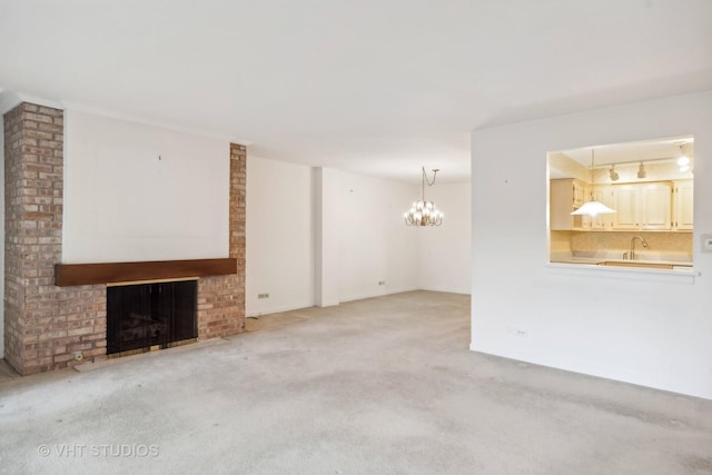 unfurnished living room featuring light carpet, a notable chandelier, a fireplace, and rail lighting