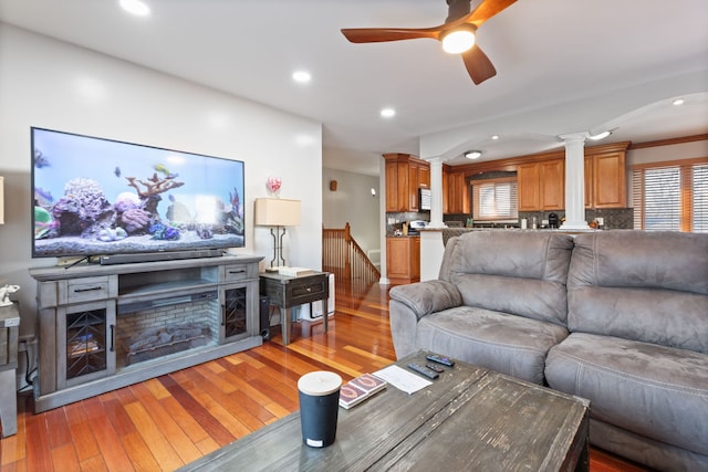 living room with ceiling fan, light hardwood / wood-style floors, ornate columns, and crown molding