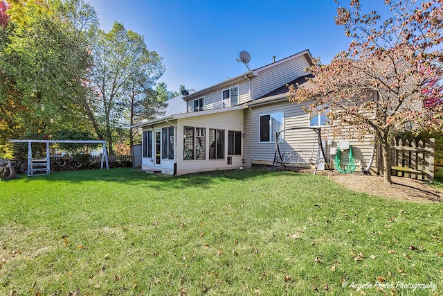 rear view of property featuring a lawn and a sunroom