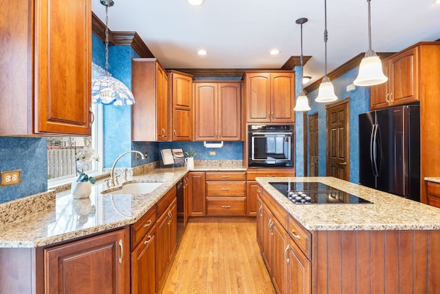 kitchen featuring black appliances, light stone counters, sink, and hanging light fixtures