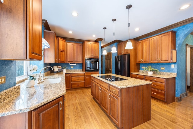 kitchen featuring black appliances, sink, hanging light fixtures, light wood-type flooring, and a kitchen island