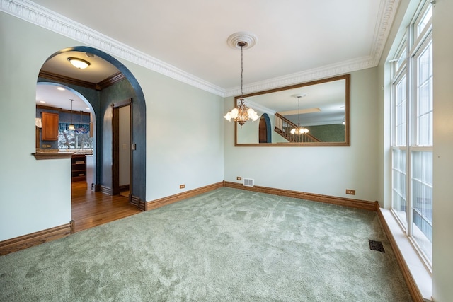 empty room featuring a notable chandelier, dark carpet, and ornamental molding