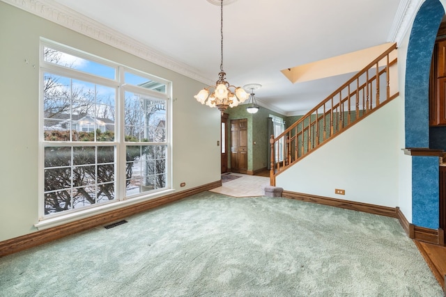 unfurnished dining area with carpet flooring, ornamental molding, and an inviting chandelier