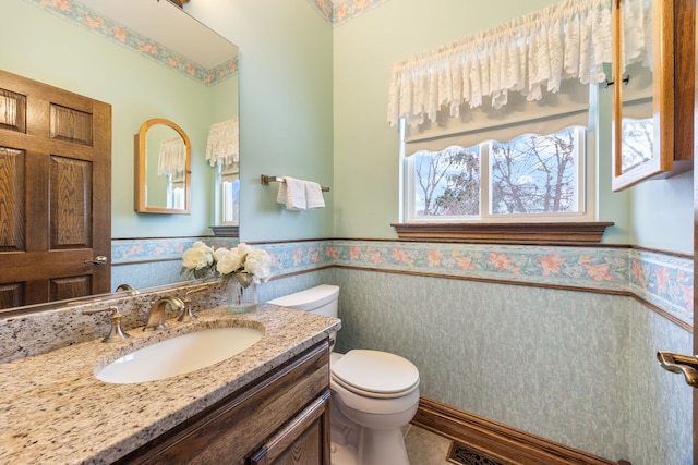 bathroom featuring vanity, a healthy amount of sunlight, and toilet