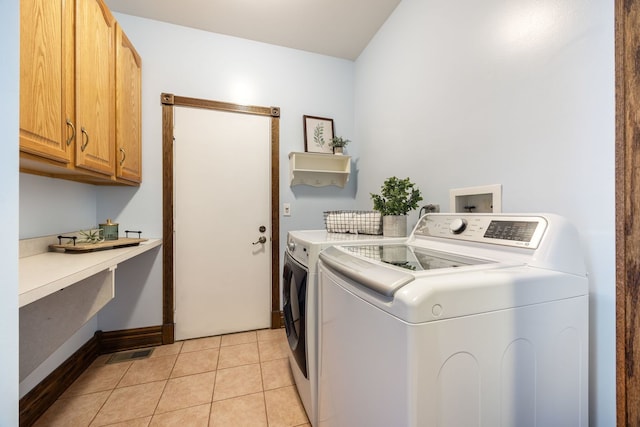 laundry room with washer and clothes dryer, cabinets, and light tile patterned floors