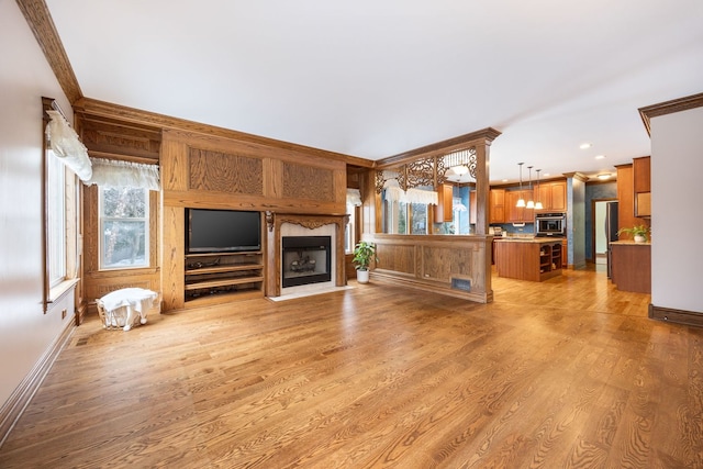 unfurnished living room with light wood-type flooring and crown molding