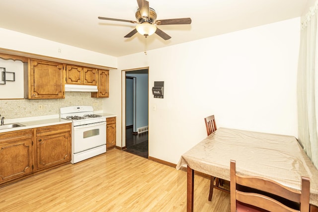 kitchen featuring tasteful backsplash, ceiling fan, white gas range oven, light hardwood / wood-style floors, and sink