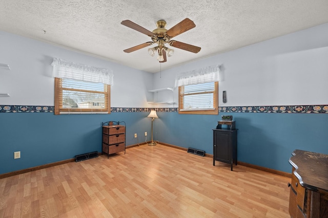 interior space featuring ceiling fan, light hardwood / wood-style floors, and a textured ceiling