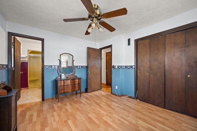 bedroom featuring a textured ceiling, light wood-type flooring, a closet, and ceiling fan