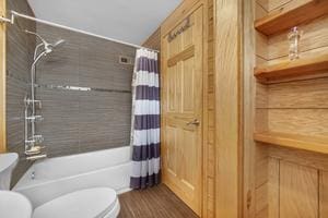 bathroom with toilet, wood-type flooring, and shower / bathtub combination with curtain