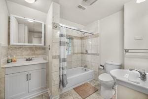 full bathroom with toilet, vanity, and tiled shower / bath