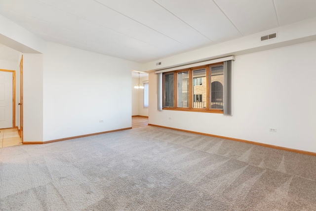 unfurnished room featuring carpet and a chandelier