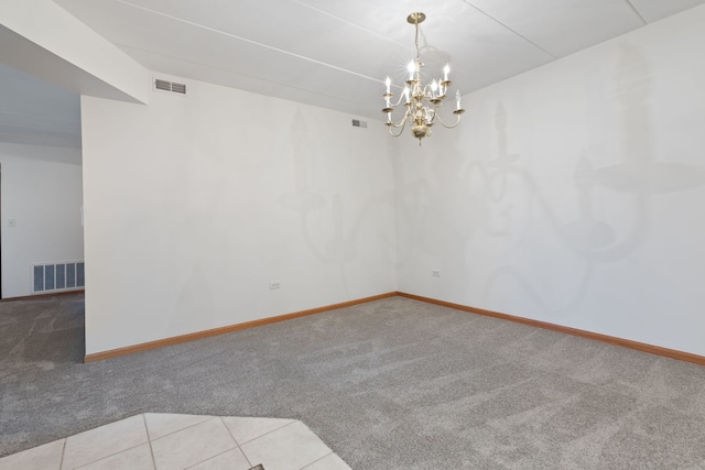 spare room featuring a notable chandelier and light colored carpet